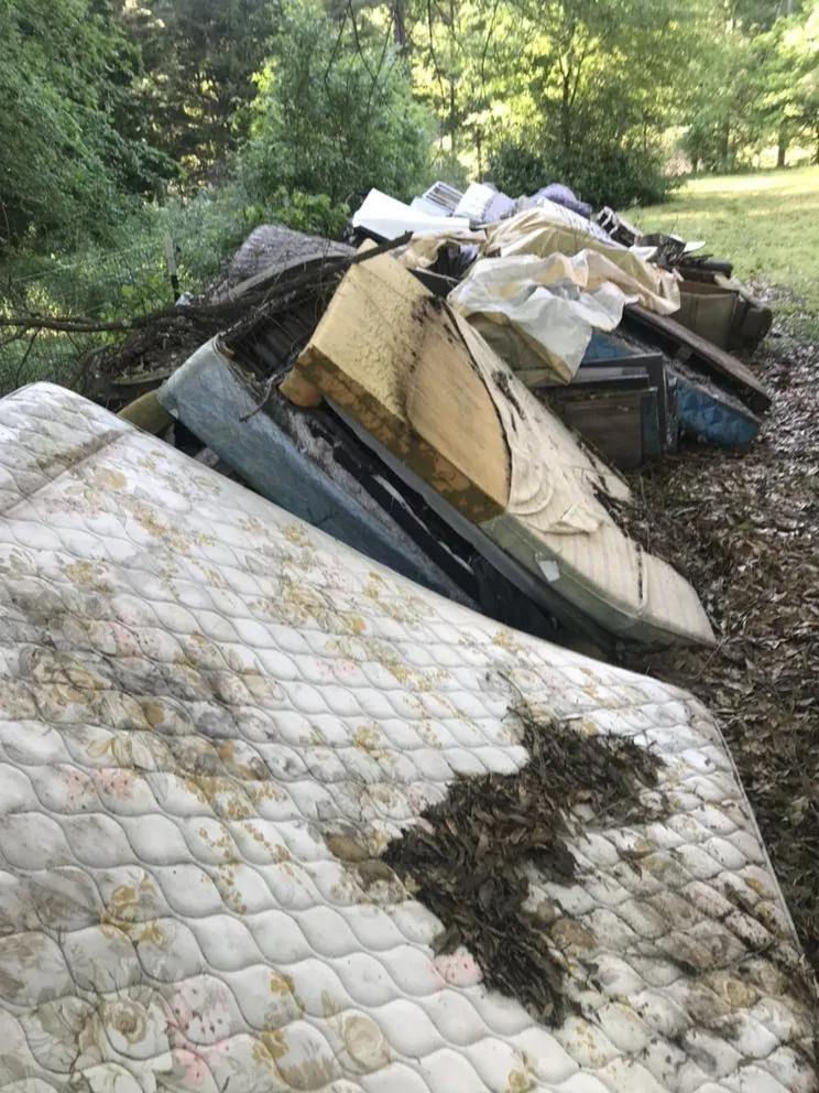 A mattress and mixed debris pile at a property