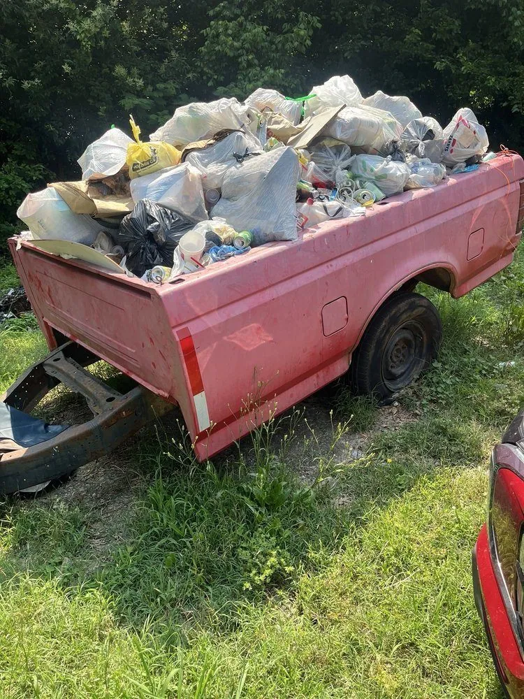 A pickup bed piled with bagged junk